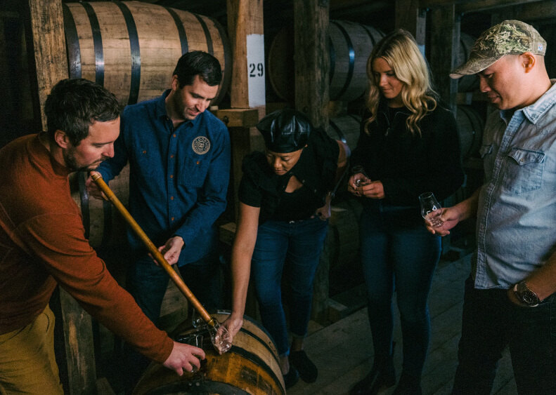 group of people serving whiskey from barrel